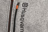 Close-up of a grey jacket with Husqvarna branding and zippered pocket.