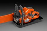 Side view of a Husqvarna chainsaw with a protective blade cover, placed on a tray.