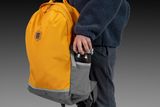 Eine Person, die einen Rucksack mit einer Flasche in der Seitentasche hält.