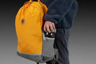 Eine Person, die einen Rucksack mit einer Flasche in der Seitentasche hält.