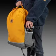 Eine Person, die einen Rucksack mit einer Flasche in der Seitentasche hält.