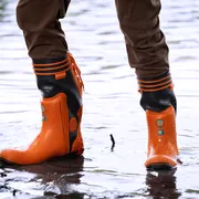 Person wearing waterproof work boots standing in shallow water.