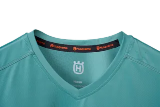 Gros plan d’un col de chemise de marque Husqvarna avec logo visible et étiquette de taille.