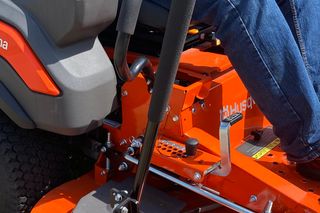 En person som använder en åkgräsklippare på en gräskant.