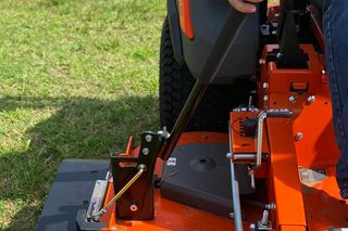 En person som använder en åkgräsklippare med fokus på manöverspakarna och klippaggregatet.