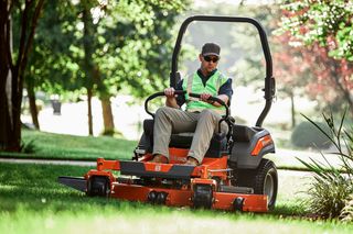 A person operating a ride-on lawn mower in a garden setting.