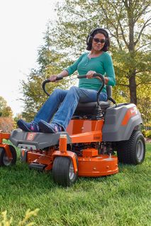 A person operating a ride-on lawn mower on a well-maintained lawn in a residential area.