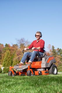 A person mowing lawn with a ride-on mower in a garden setting.