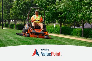 A person mowing lawn with a ride-on mower in a park setting.