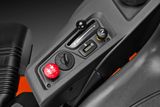 Close-up de um painel de controlo num trator corta-relva, com uma chave de ignição e vários controlos.