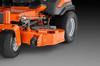 Close-up view of a Husqvarna ride-on mower's cutting deck and front wheel.