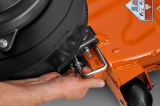 Close-up of a person adjusting a component on a lawn mower.