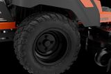 Close-up view of a ride-on mower's rear wheel and cutting deck.