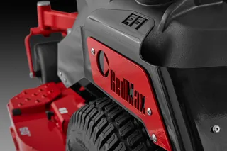 Close-up view of a RedMax branded lawn mower with visible tire and deck components.