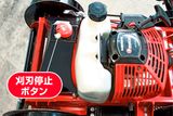 ブレードストップボタンと燃料タンクを示す芝刈り機の上面図。