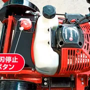 ブレードストップボタンと燃料タンクを示す芝刈り機の上面図。